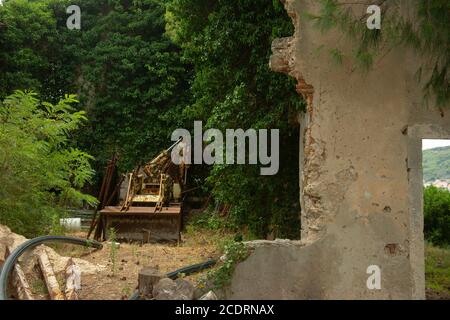 A rusty tractor loader sits abandoned in a collapsed barn. Stock Photo
