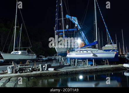 Cagliari, Sardinia, Italy - August 28 2020: boat lift out of the water by an heavy crane machine in the city pier at night Stock Photo