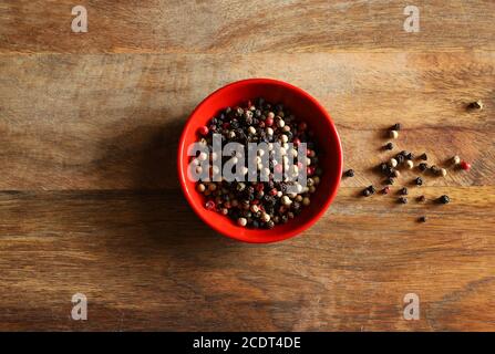 A bowl with colorful pepper seeds on wooden background. Directly above. Stock Photo