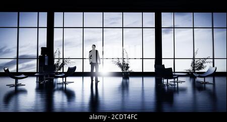 Business man standing in the office looking out of the window at sunset sky. Stock Photo
