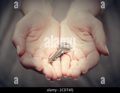 Key in woman#39;s hand in gesture of giving. Concept of success in live, business solution, real estate etc Stock Photo