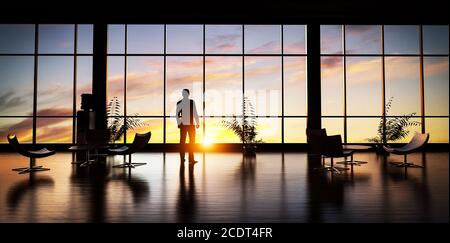 Business man standing in the office looking out of the window at sunset sky. Stock Photo