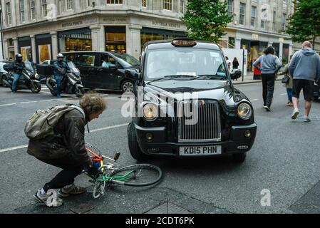 London, UK.  29 August 2020.  A cyclist recovers after being knocked down by a taxi on Sloane Street in Knightsbridge.  The cyclist appeared not seriously injured and was able to stand and collect his mangled bicycle. Credit: Stephen Chung / Alamy Live News Stock Photo