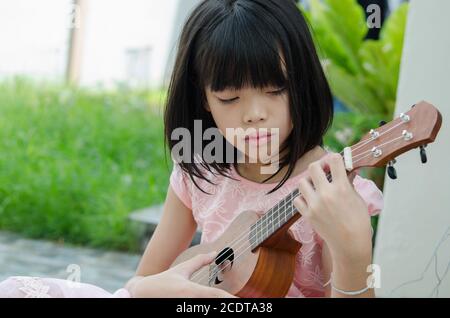 Asian girl playing the ukulele Stock Photo