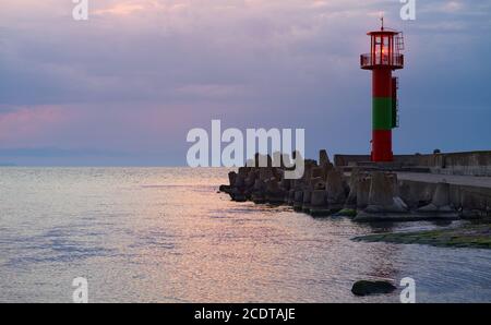 Lighthouse protected by concrete breakwater tetrapods at sunset, Swinoujscie, Poland. Stock Photo