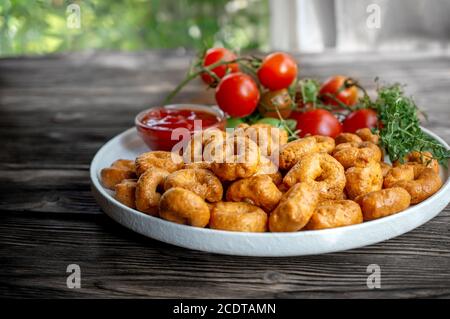 handmade tarallini with tomatoes and herbs called taralli or TARALLINI in Italian bakeries in southern Italy on a wooden background Stock Photo