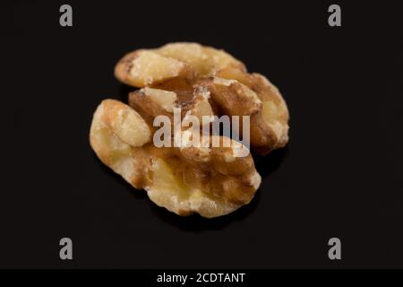 macro shot of a single walnut half on a black background with slight reflection Stock Photo