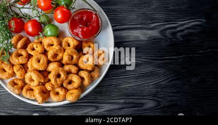 handmade tortellini with tomatoes and herbs is called taralli or TARALLINI in Italian bakeries in southern Italy on a wooden background. Top view Stock Photo