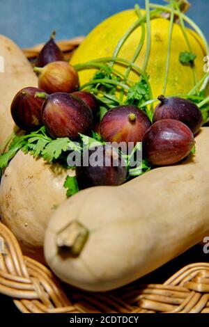 Still life of fresh figs, cilantro and butternut squash in a wicker basket. Stock Photo
