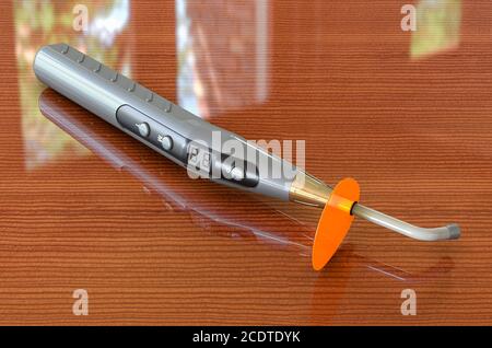 Wireless dental curing light LED on wooden table, 3D rendering Stock Photo