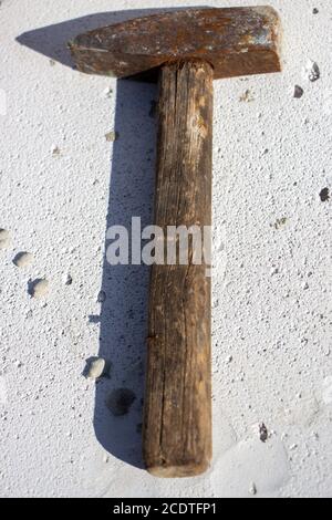 An old hammer on a white foam concrete block from which the shadow falls Stock Photo
