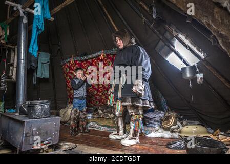 A Nenet boy and child inside a chum (traditional tent covered with reindeer hides), Yamalo-Nenets Autonomous Okrug, Russia Stock Photo