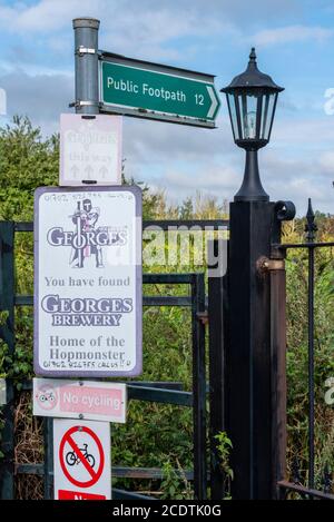 Public footpath 12, George's Brewery signs in Great Wakering, near Southend, Essex, UK. Kissing gate access to footpath onto farm and business Stock Photo