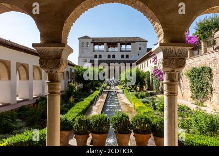 View of The Generalife courtyard, with its famous fountain and garden through an arch. Alhambra de Granada complex at Granada, S Stock Photo