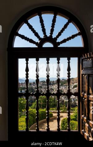 View of the Albayzin district of Granada, Spain, from an arched window grill in the Alhambra palace near sunset at Granada, Spai Stock Photo