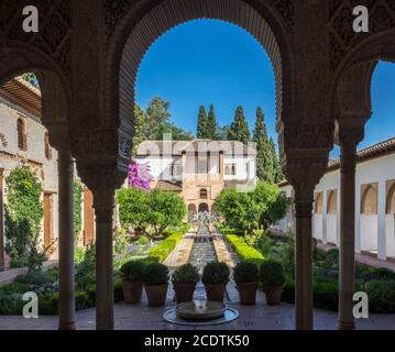 View of The Generalife courtyard, with its famous fountain and garden through an arch. Alhambra de Granada complex at Granada, S Stock Photo