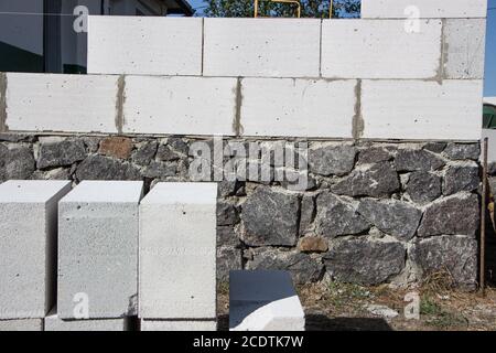 Construction of a house from aerated concrete materials lying near the stone foundation. Stock Photo