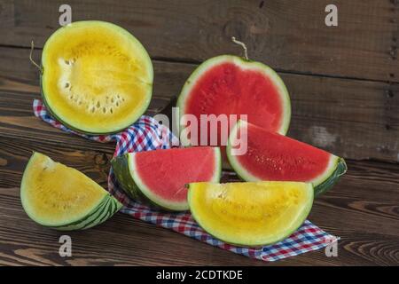 Cut red and yellow watermelons on a wooden box in a vintage wooden background in rustic style, selective focus, toned photo. Stock Photo