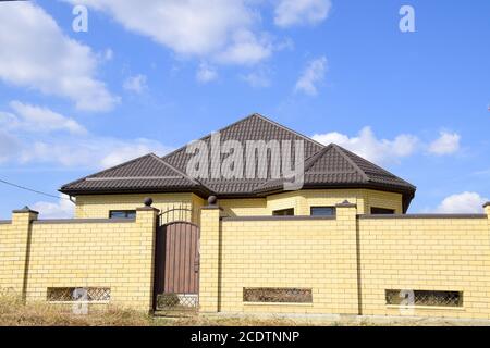 Decorative metal on the roof of a brick house. Fence made of corrugated metal. Stock Photo