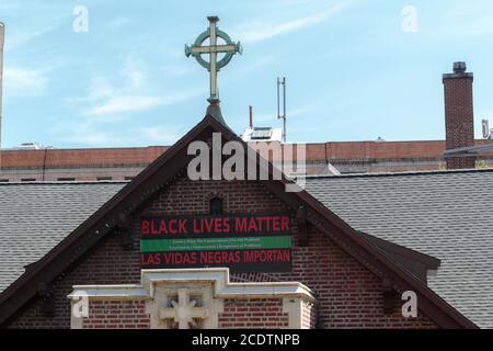 a Black Lives Matter sign hanging above the entrance of Fort Washington Collegiate Church in Northern Manhattan underneath a cross Stock Photo