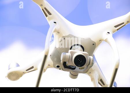 Drone DJI Phantom 4 in flight. Quadrocopter against the blue sky Stock Photo