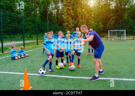 Kids in football uniform listening to explain of coach on training Stock Photo