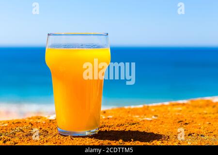 Glass filled with orange juice at sea Stock Photo