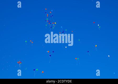Multicolored balls, filled with helium, fly in the blue sky Stock Photo