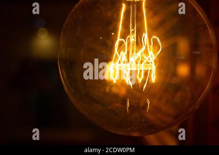 Close-up golden shining antique Edison style bulb in the dark. Lighting decor concept. Vintage light bulb Stock Photo
