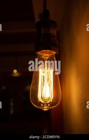 Golden shining antique Edison style bulb in the dark. Lighting decor concept. Vintage light bulb Stock Photo
