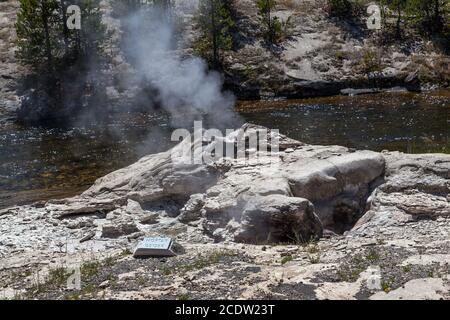 Mortar Geyser on the bank of the Firehole River, releasing steam on a sunny summer day in Yellowstone National Park, Wyoming. Stock Photo