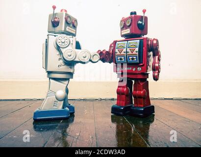 two vintage robot shake hands on a old wooden floor Stock Photo