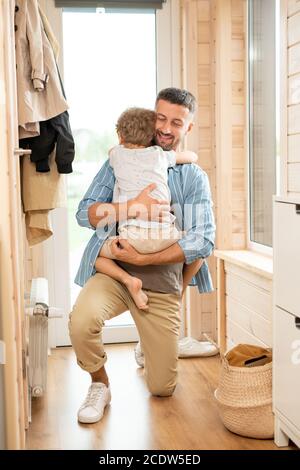 Happy young careful and affectionate father embracing cute little son at home Stock Photo
