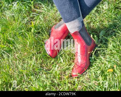 Young girl in red paddock boots with long tighs sitting in grass and waiting for her horse and lesson. Stock Photo