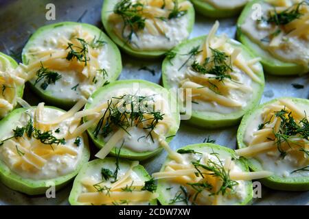 raw zucchini with cheese on baking sheet Stock Photo