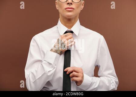 Young contemporary businesswoman in white shirt and putting on black tie Stock Photo