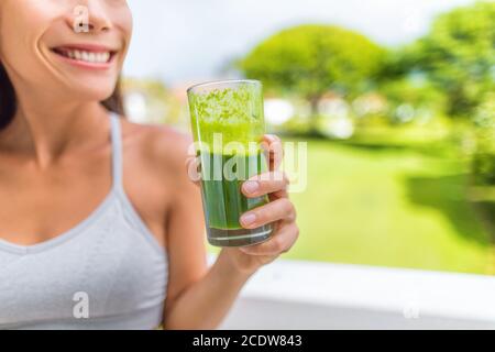 Green smoothie healthy lifestyle fitness woman drinking spinach juice cleanse in summer background at home. Happy fit girl living active life juicing Stock Photo