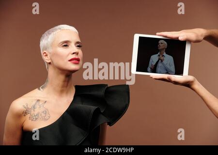 Human hands holding tablet with elegant woman on its screen in front of female Stock Photo