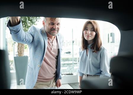 Elegant mature man and his brunette pretty wife looking in trunk of car Stock Photo