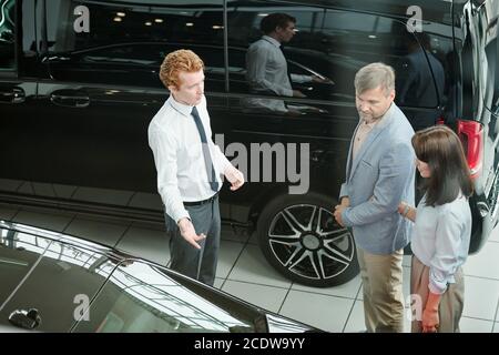 Middle aged consumers in smart casualwear listening to young sales manager Stock Photo