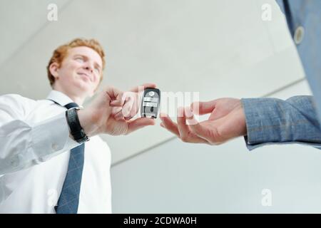 Hand of male buyer going to take remote control alarm system of new car Stock Photo