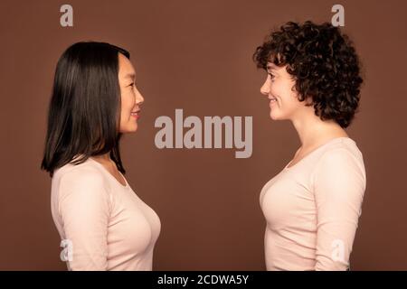 Side view of two cheerful young females of Asian and Caucasian ethnicities Stock Photo