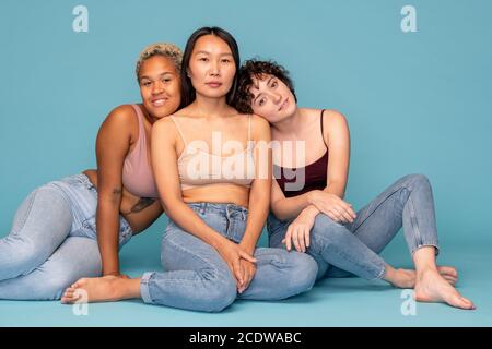Three young affectionate and friendly women in tanktops and blue jeans Stock Photo