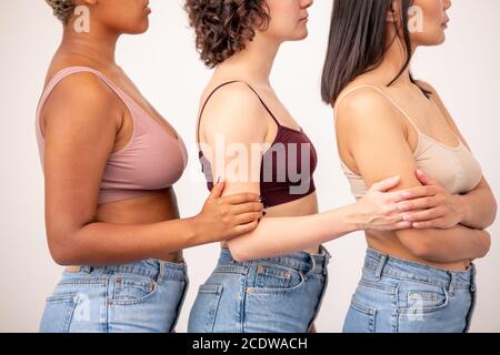 Side view of three young women of various ethnicities in tanktops and blue jeans Stock Photo