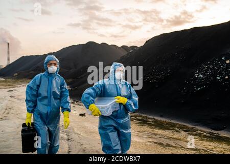 Two female ecologists in coveralls, respirators, eyeglasses and rubber gloves Stock Photo