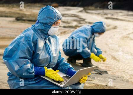 Ecologist entering data about characteristics of polluted water and soil Stock Photo