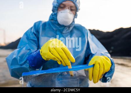 Ecologist putting flask with sample of water from dangerous area into packet Stock Photo