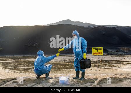 Contemporary ecologist in protective workwear taking sample of polluted water Stock Photo