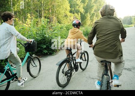 Active family of husband, wife and their son of elementary age riding bicycles Stock Photo