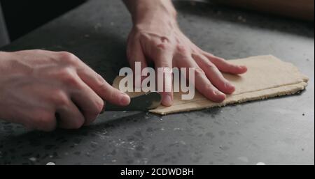 man cutting flat dough with knife, wide photo Stock Photo